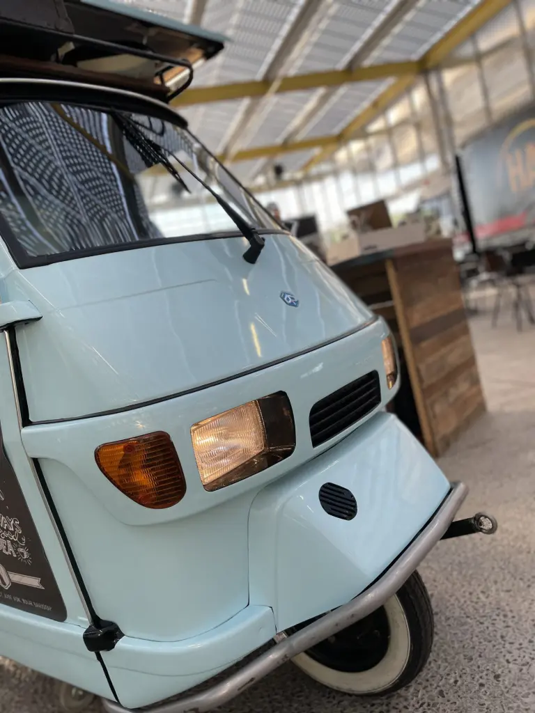 Voorkant van een lichtblauwe Piaggio Ape koffiewagen van Barista Company