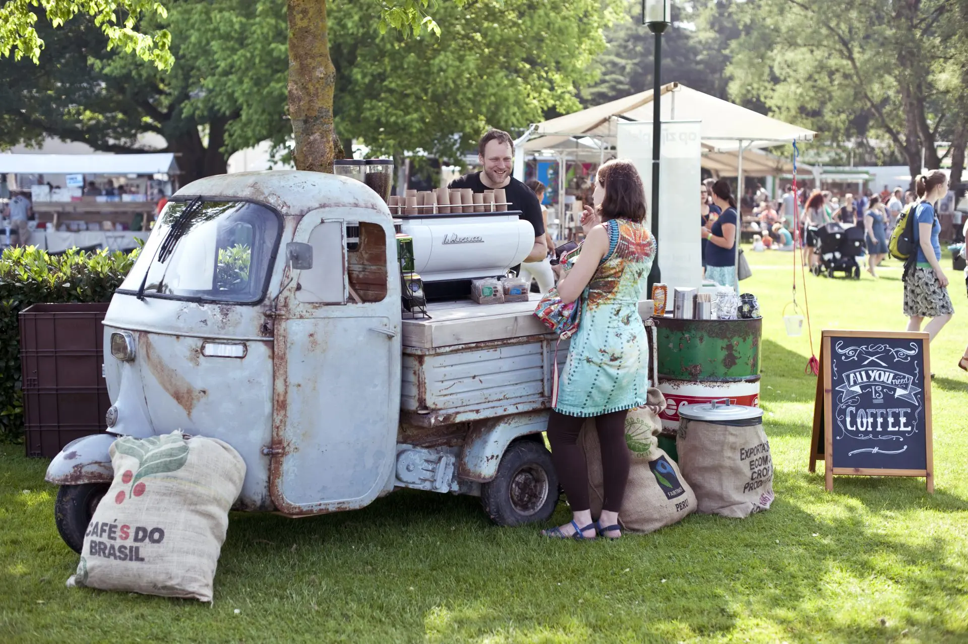 Vintage Piaggio koffiewagen met barista en gasten op een buitenevenement